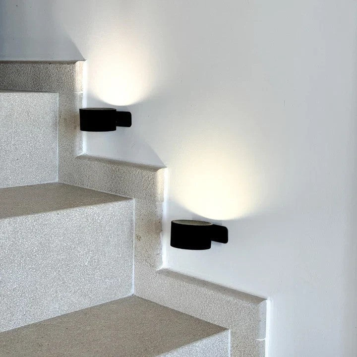 Pair of black stairway lights illuminating concrete steps with warm glow