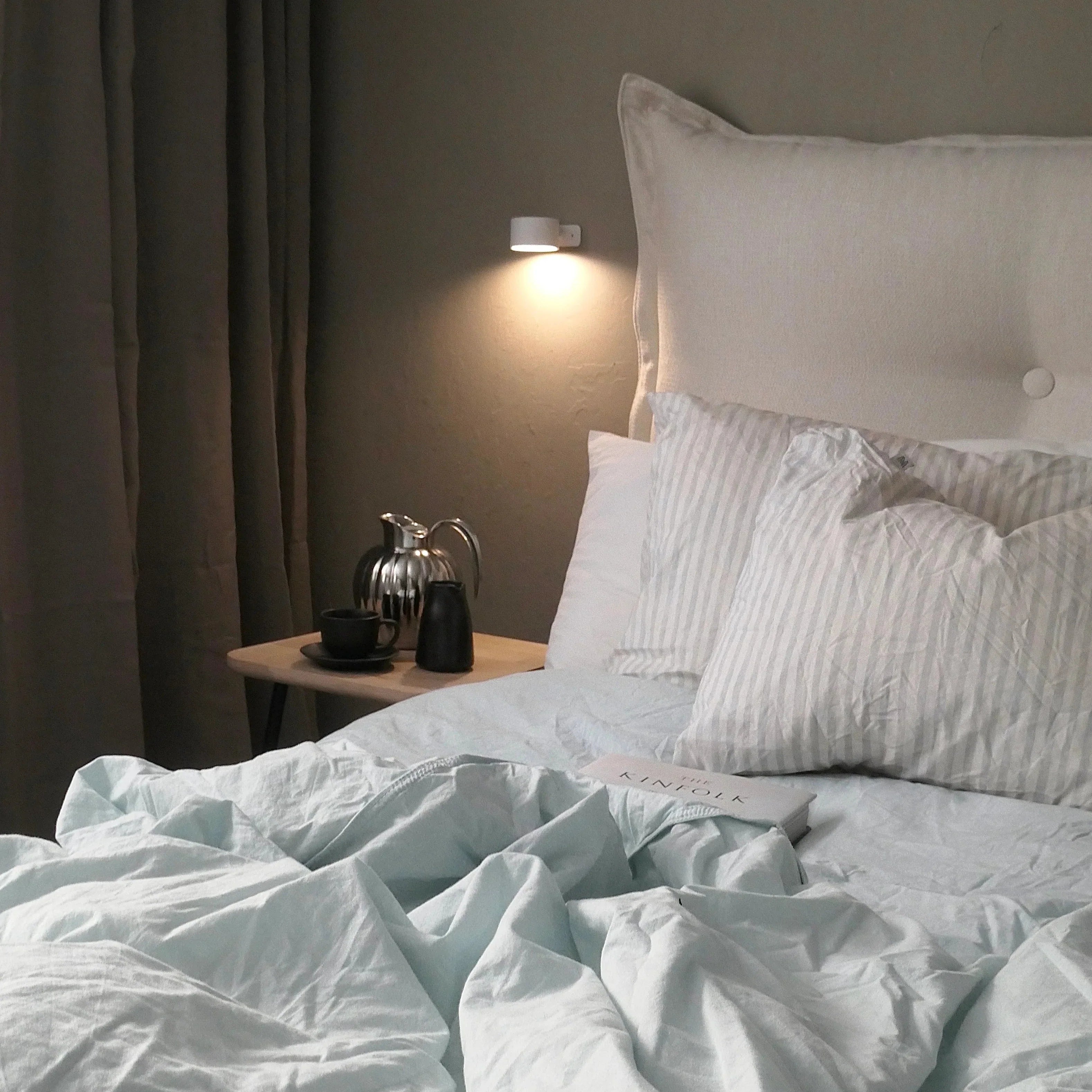 White cylindrical task lighting above modern bedside table setup