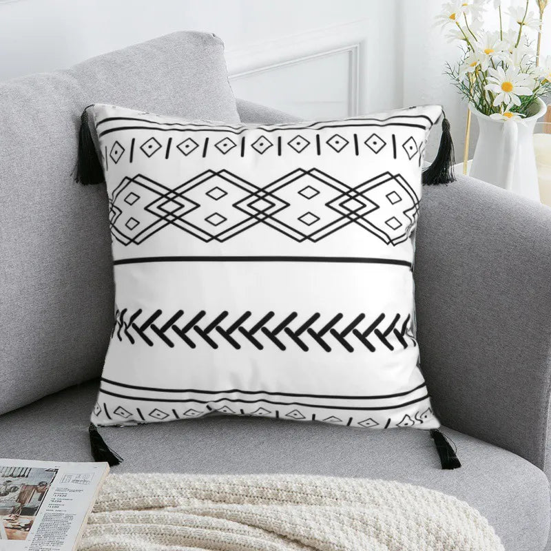 Tribal hexagon and zigzag pattern cushion with black tassels on gray fabric sofa