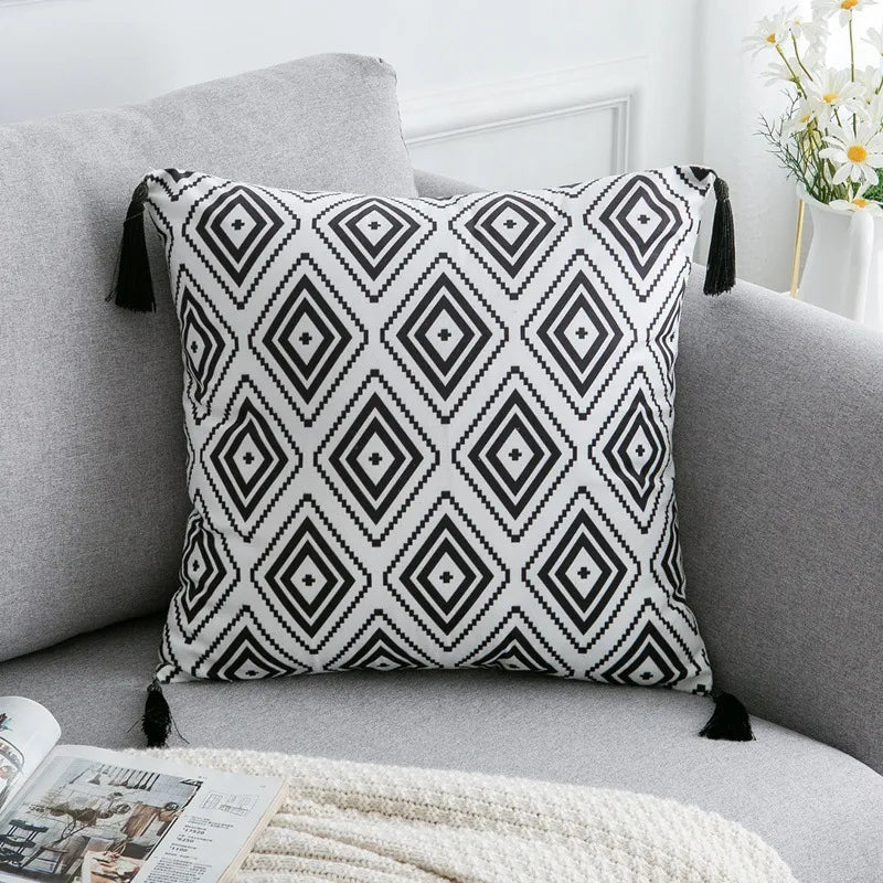 White throw pillow with pixelated black diamond motifs and corner tassels