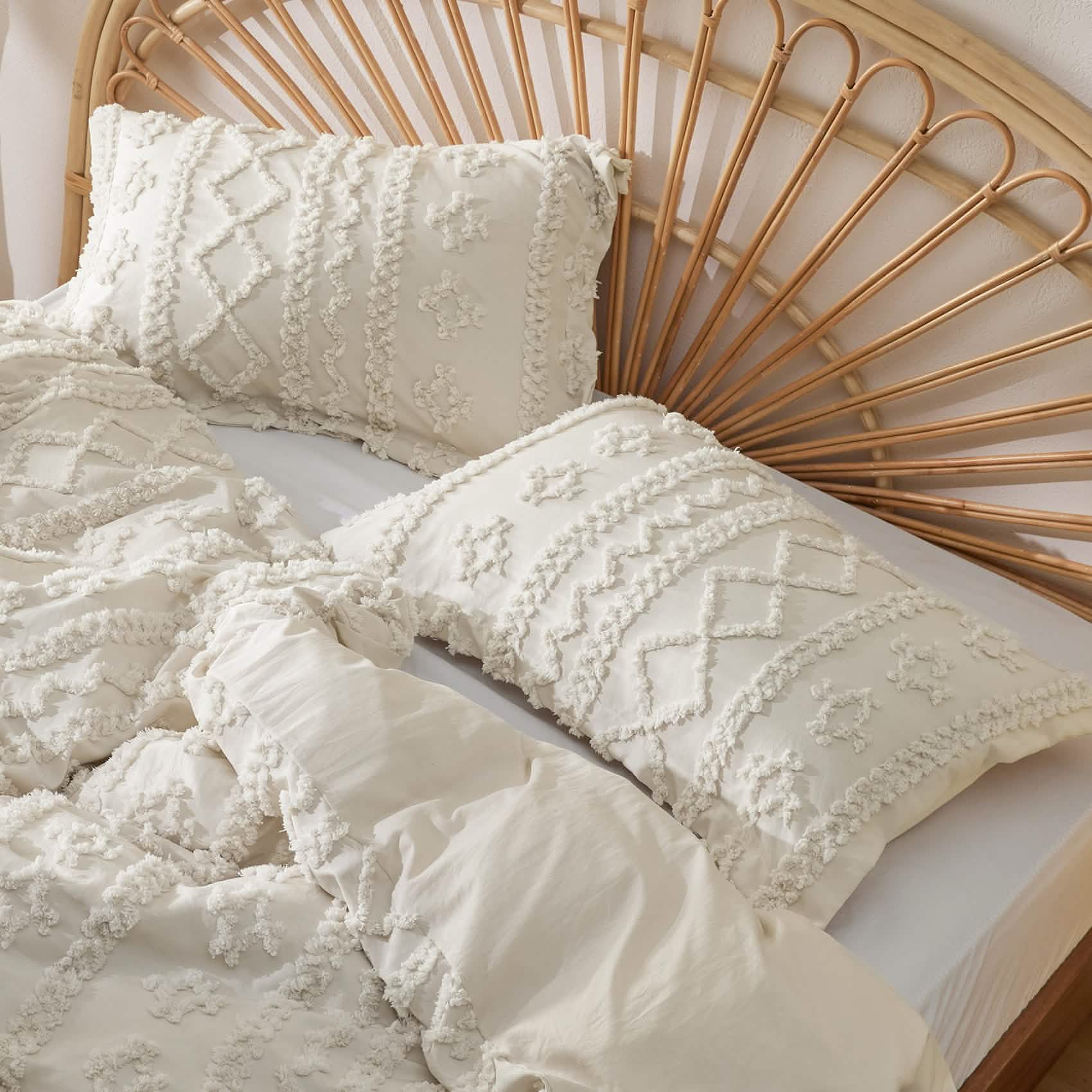 Cream textured duvet cover set on rattan headboard with pillow shams