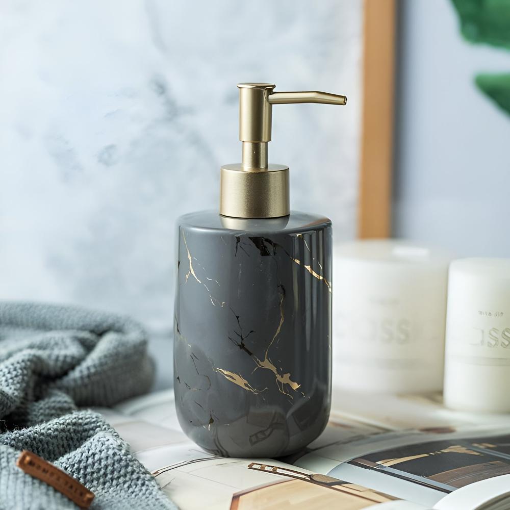 Dark gray ceramic soap dispenser with black and gold marble pattern beside candles