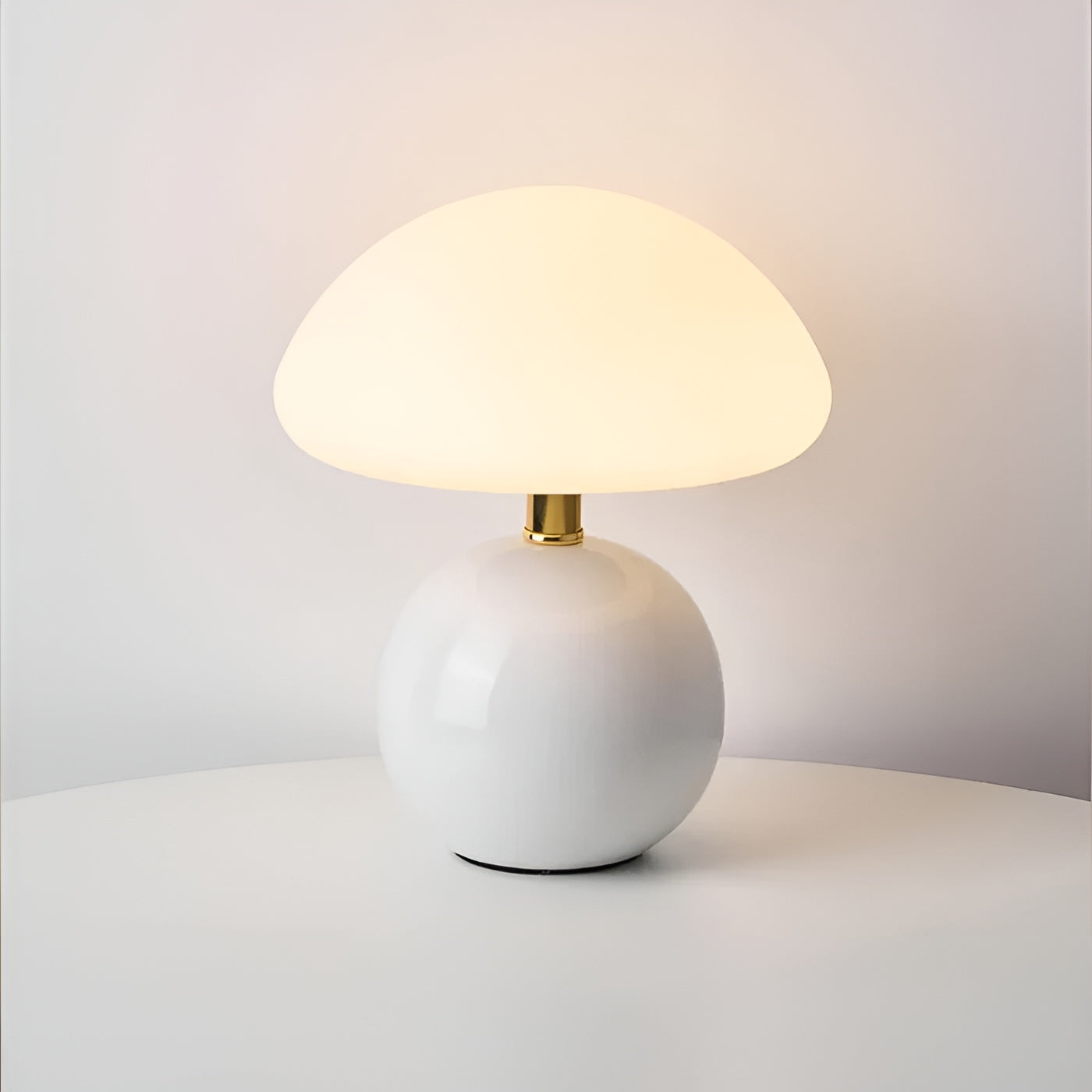 White glossy sphere table lamp with gold trim and warm yellow light