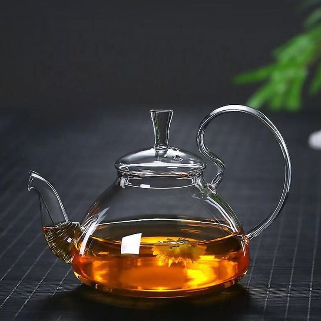 Borosilicate glass teapot with ribbed spout base holding yellow blooming flower tea