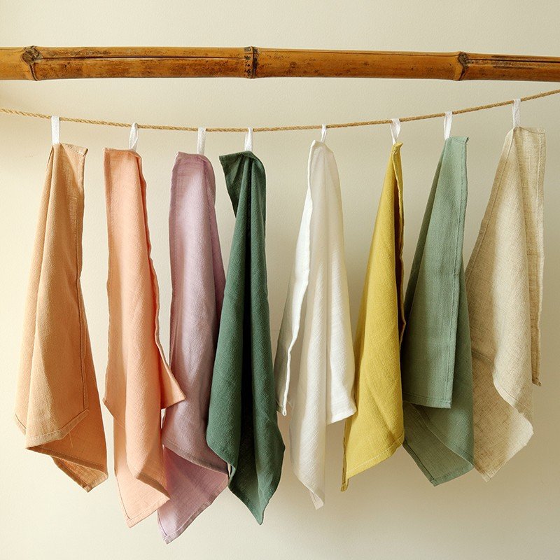 Set of eight solid color cotton linen napkins hanging on bamboo pole