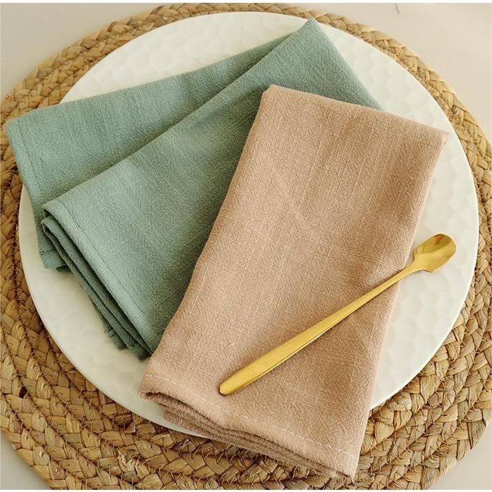 Sage green and dusty rose cotton linen napkins on rattan placemat