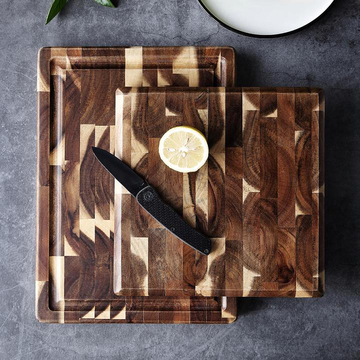 Small end grain cutting board with sliced lemon and knife on larger board
