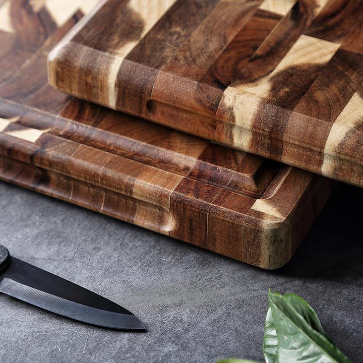 Stacked end grain wood cutting boards with handle cutout and black knife