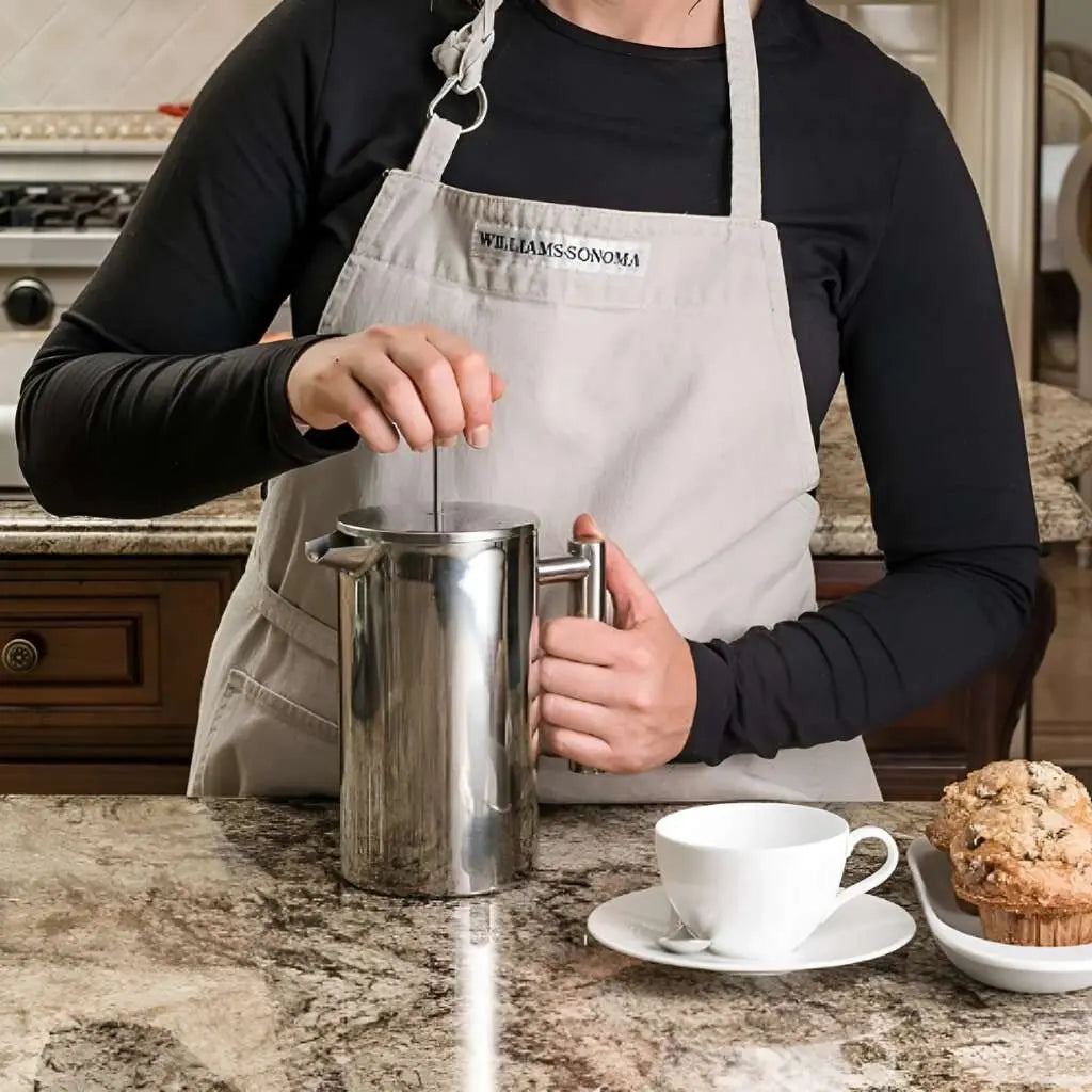 Person pressing plunger on insulated stainless steel French press for morning coffee