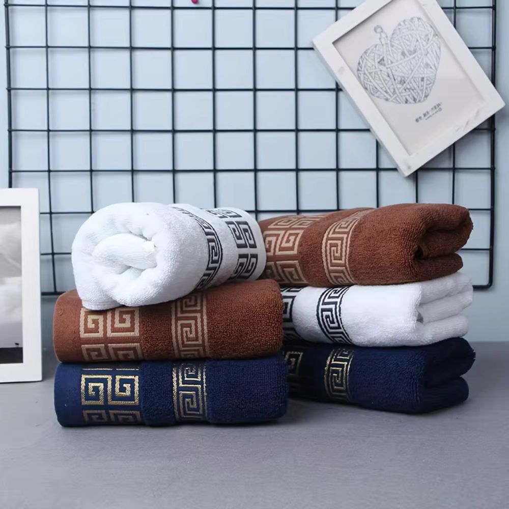Stacked white and brown towels with gold or black Greek key borders