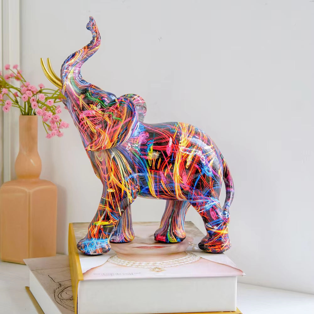 Colorful graffiti elephant statue with gold tusks on books