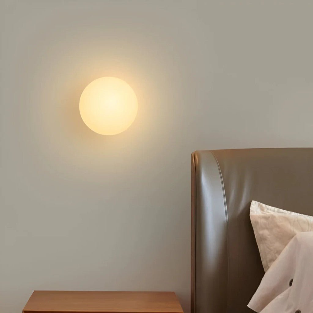 Frosted glass orb sconce above wooden nightstand for bedroom ambiance