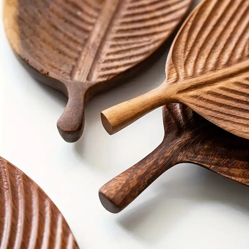 Stacked leaf shaped wooden trays showing multiple wood tone finishes