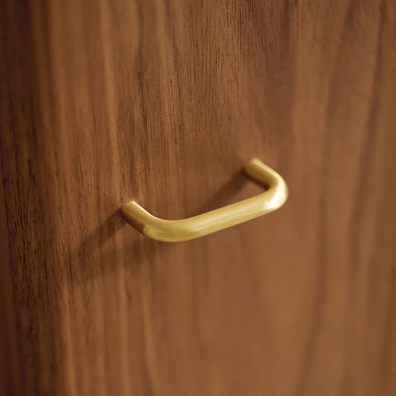 Matte gold curved handle on dark walnut jewelry cabinet door