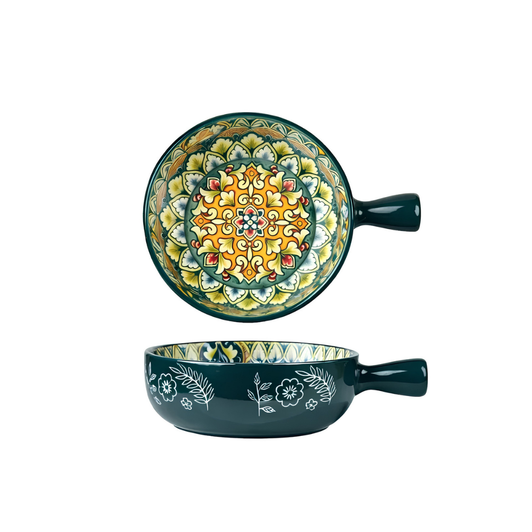 Dark teal ceramic bowl with single handle showing yellow green and red mandala pattern inside