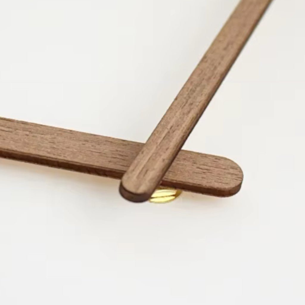 Close-up of brown wooden clock hands with gold pivot point detail