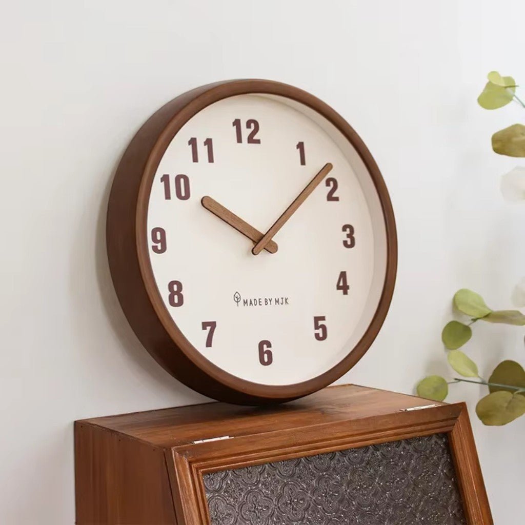 Wooden wall clock with cream dial mounted above cabinet with greenery