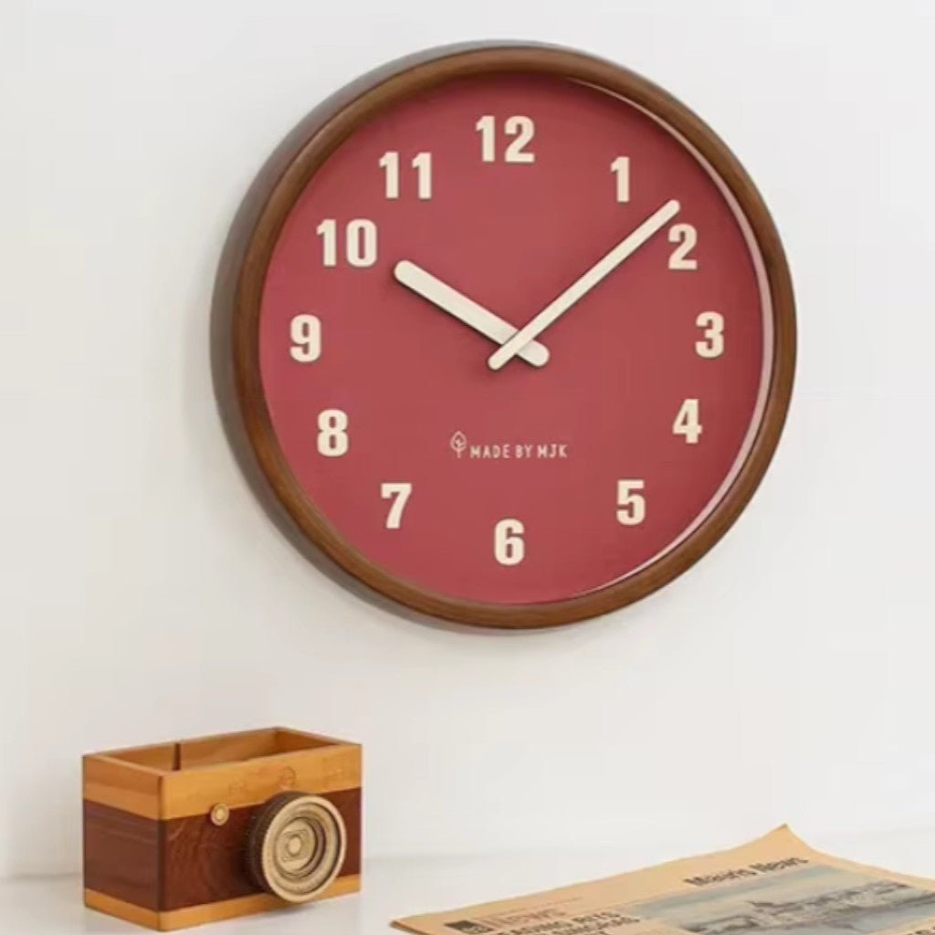 Mid Century wooden wall clock with red dial and white numerals on white wall
