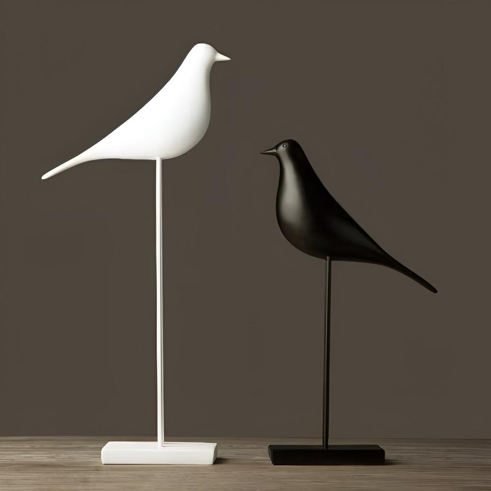 Contrasting black and white minimalist bird statues on wooden surface