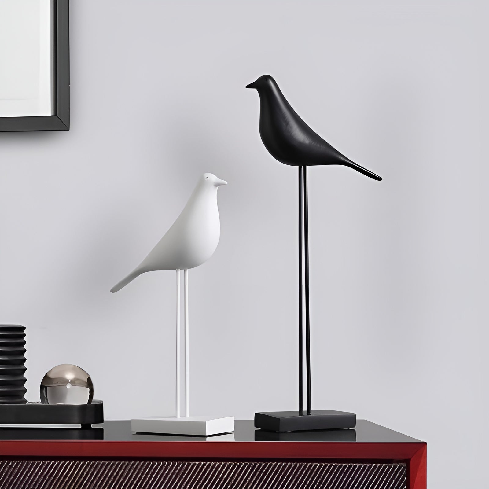 Black and white minimalist bird figurines contrasting on red console table