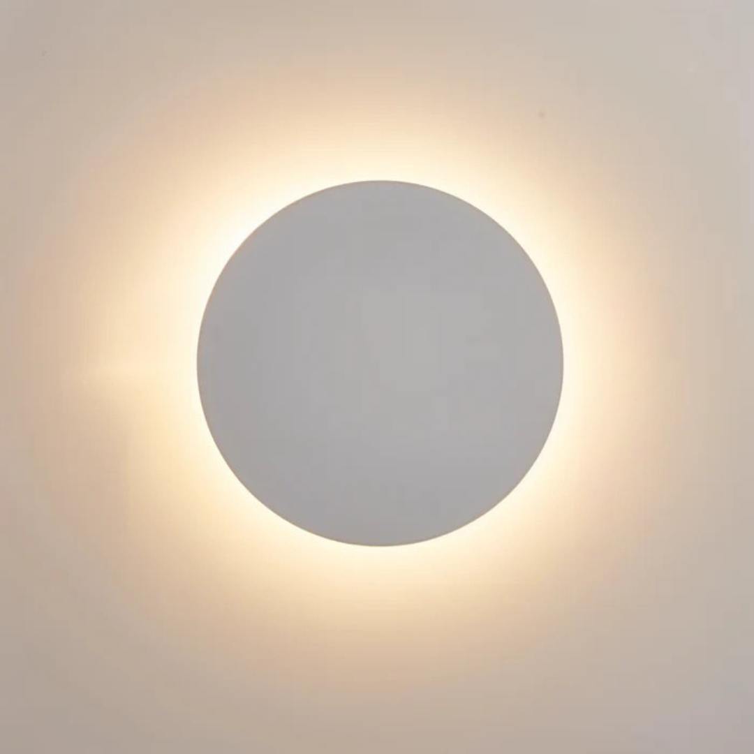 Minimalist black disc wall sconce highlighting flat modern silhouette