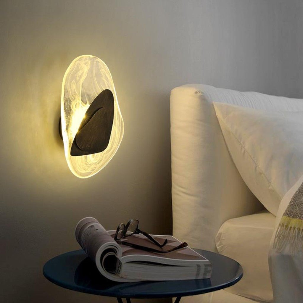 Black metal triangle detail on organic glass wall sconce in bedroom setting
