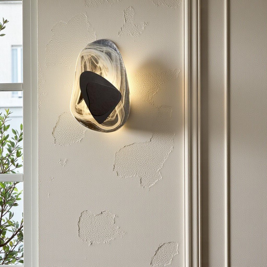 Black geometric triangle wall sconce casting warm glow on stucco wall