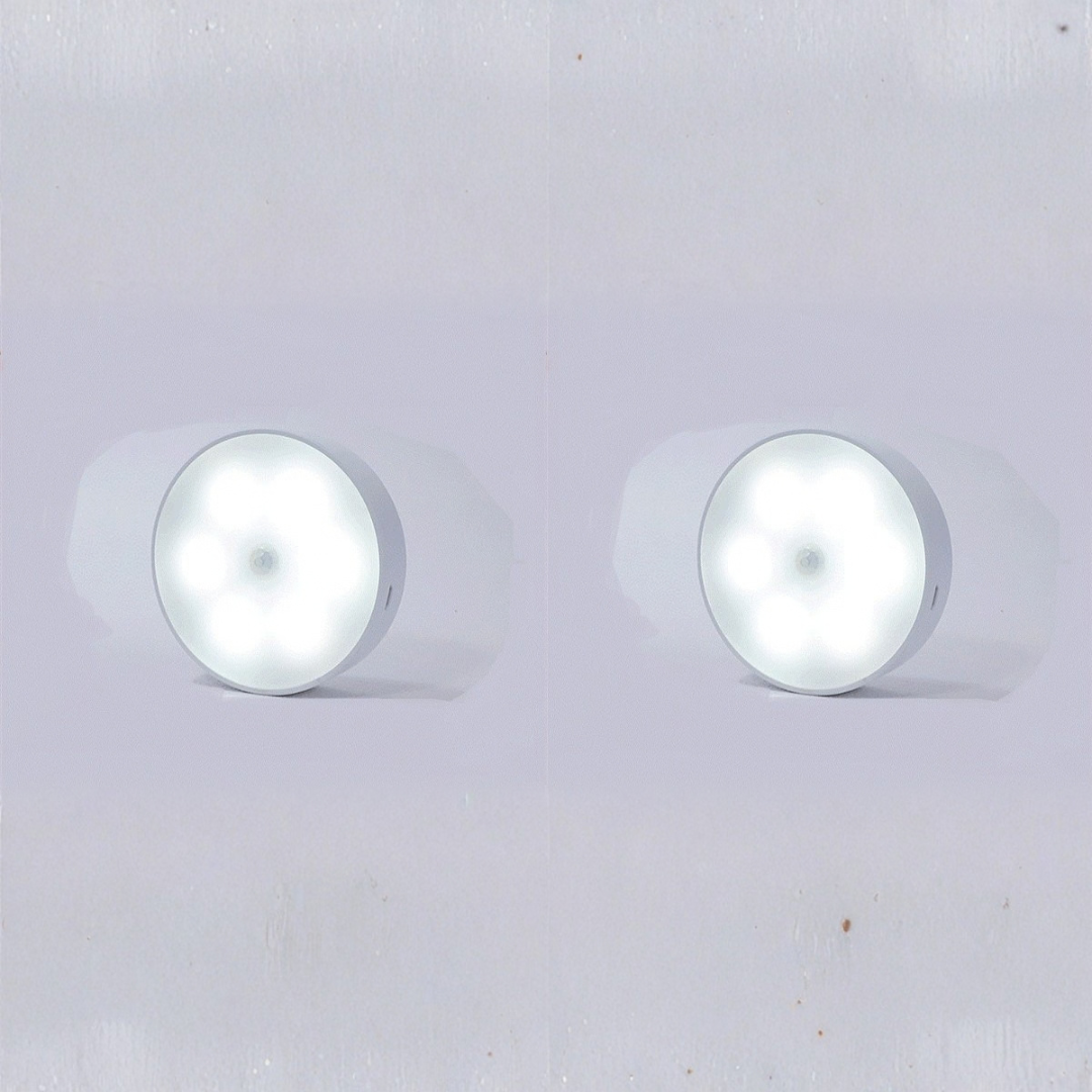 Close-up of two wireless puck lights showing central motion sensor details