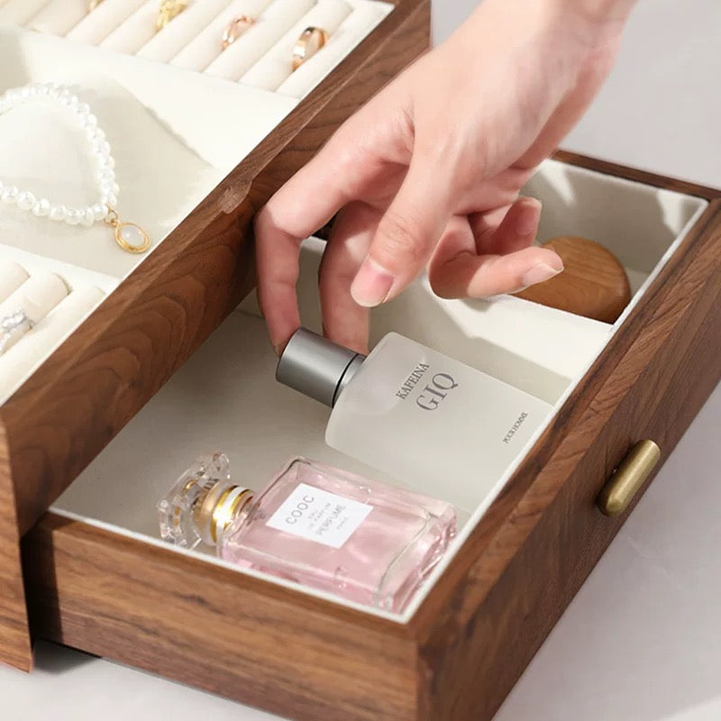 Close-up of open lower drawer in walnut wood jewelry box revealing cream velvet lining and perfume storage