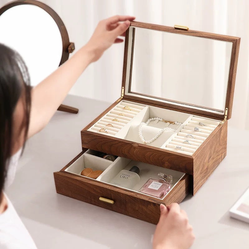 Person opening dark walnut jewelry box with glass lid to reveal multi-compartment ring and necklace storage