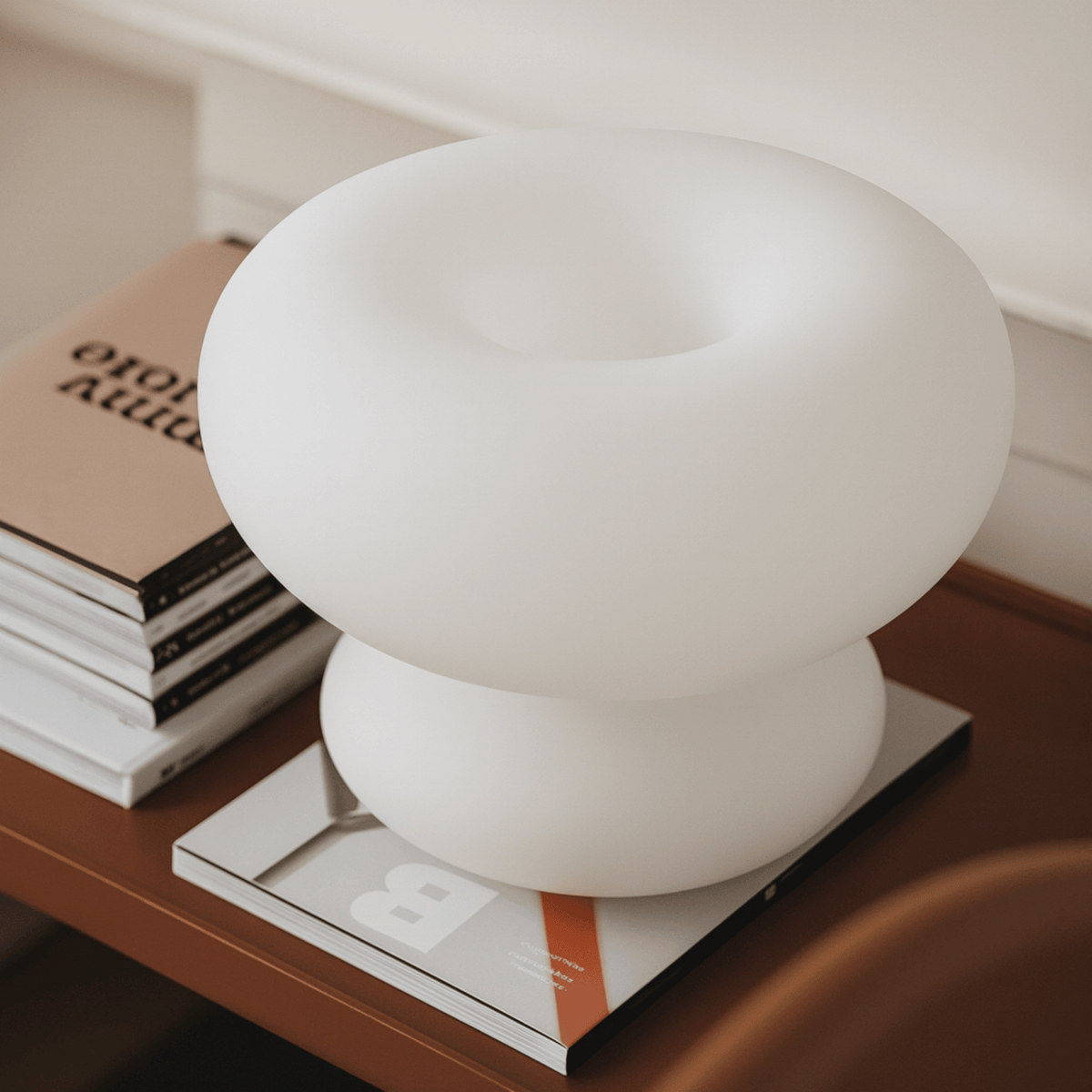 Unlit matte frosted glass donut bedside light stacked on books for modern decor