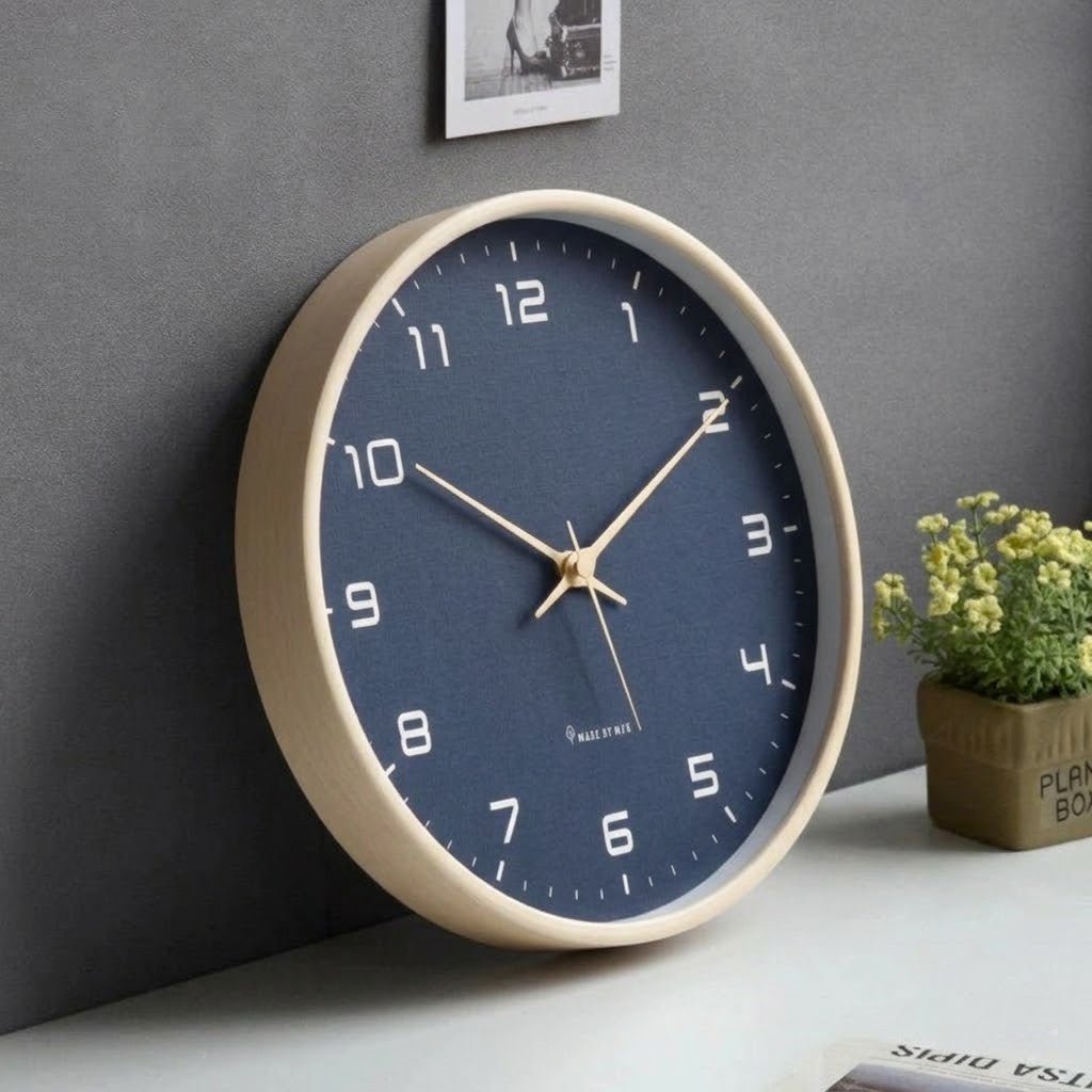 Nordic style navy blue wood frame wall clock on white surface with plant