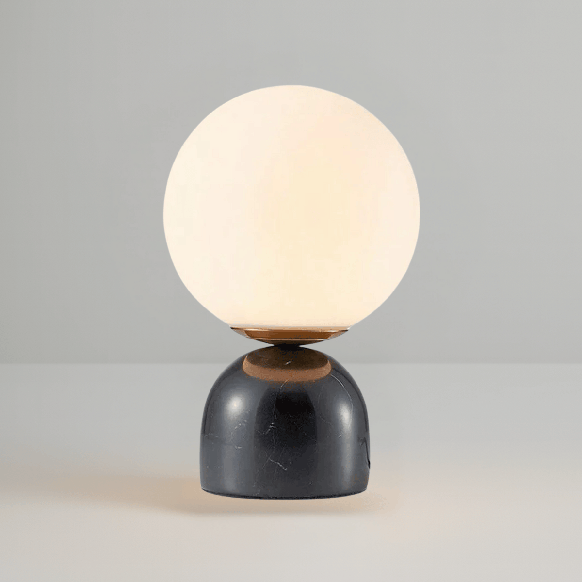 Black marble dome base table lamp with bronze connector and frosted glass sphere