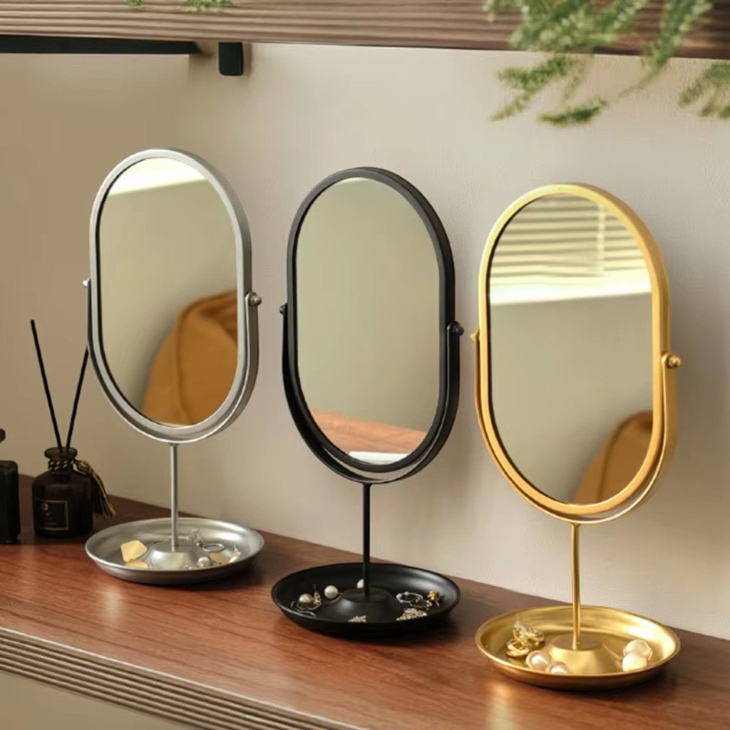 Silver, black, and gold oval vanity mirrors arranged on wooden shelf