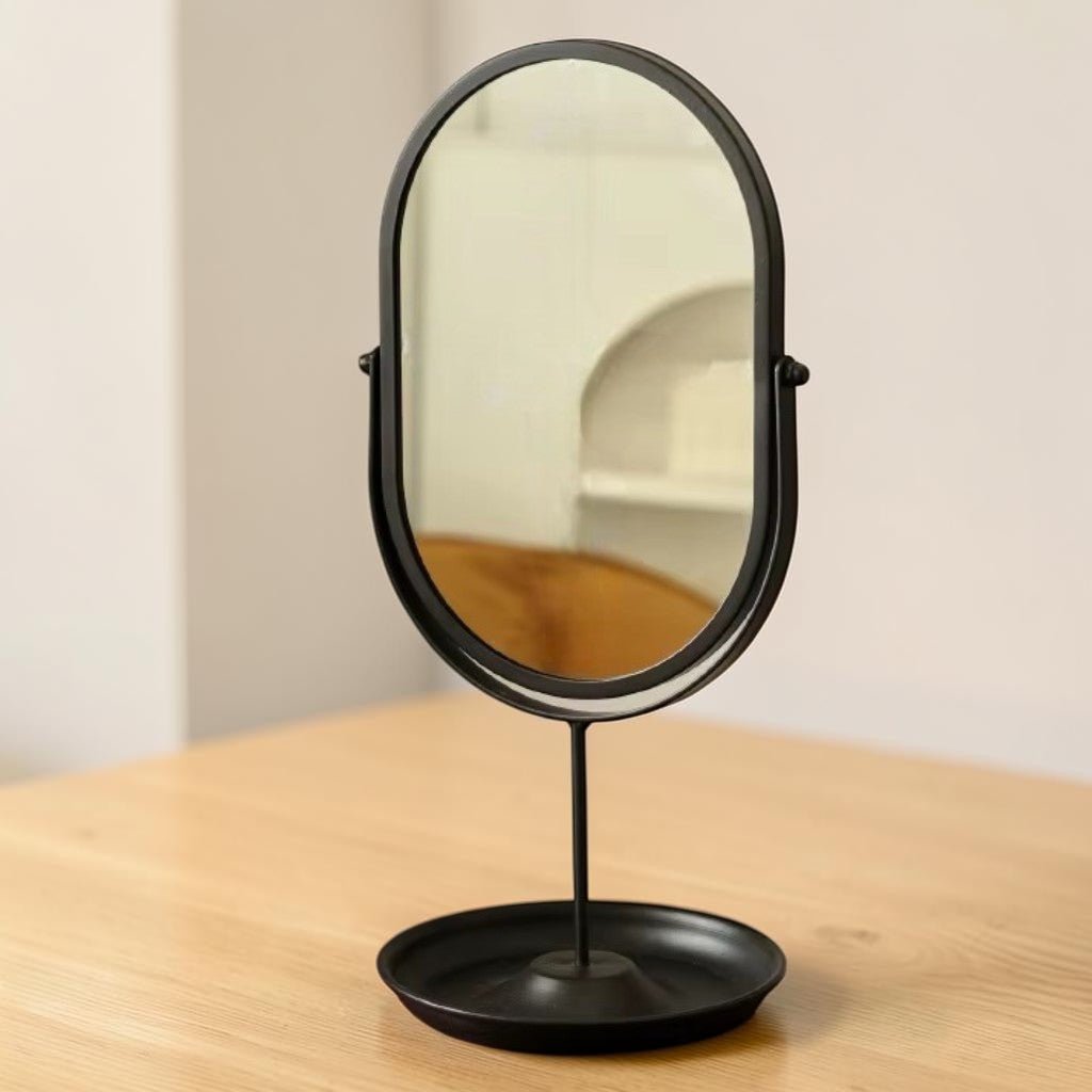 Matte black oval vanity mirror with rotating iron stand on wood surface
