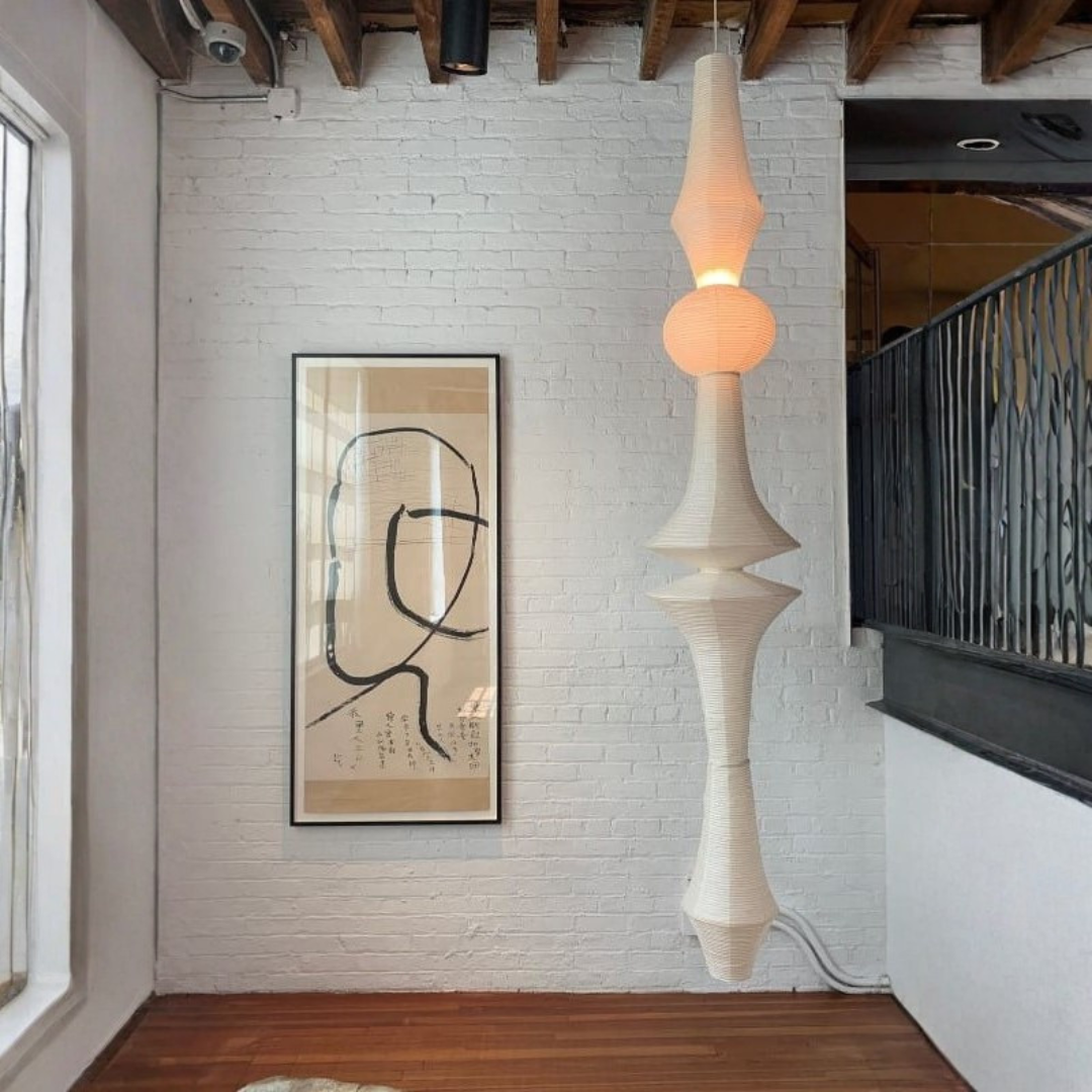 Cream sculptural paper lantern hanging in stairwell with brick wall