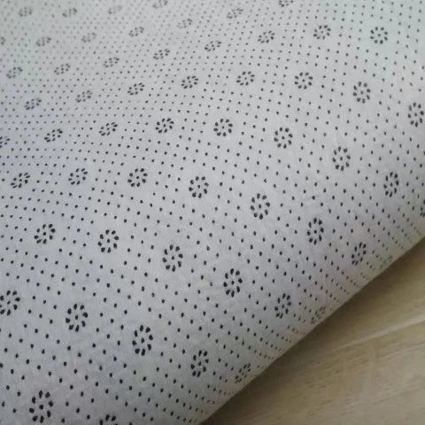 White bath mat with black floral dot pattern and rolled thickness detail