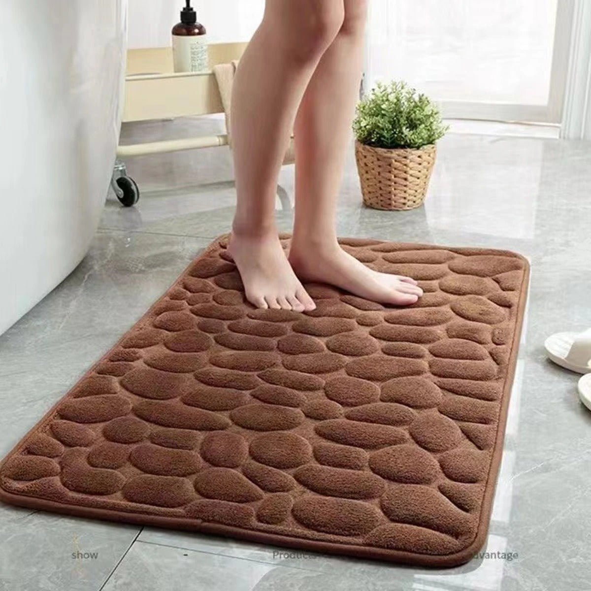 Brown plush 3D cobblestone bath mat with rounded edges on gray tile