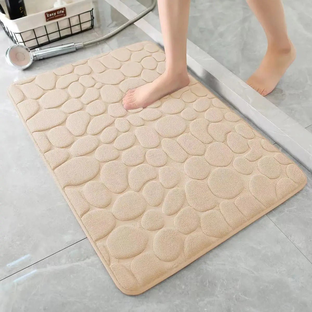 Beige absorbent shower mat with irregular cobblestone pattern on tile