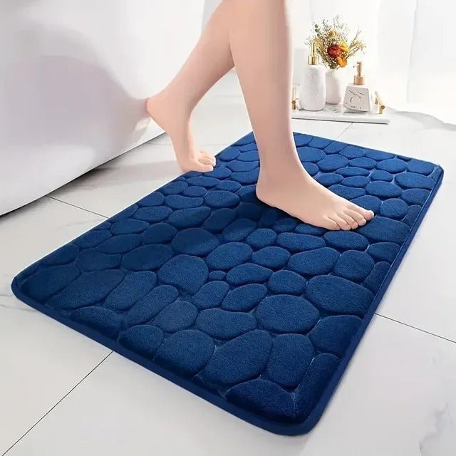 Deep blue non-slip bath mat with raised texture near bathtub window
