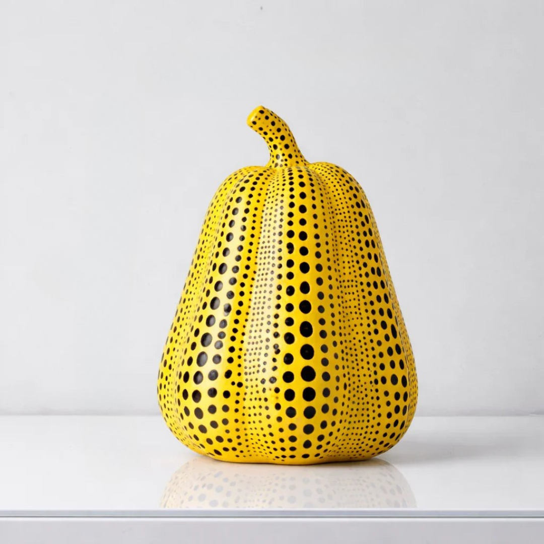Yellow resin pumpkin sculpture with black polka dots and ribbed texture detail