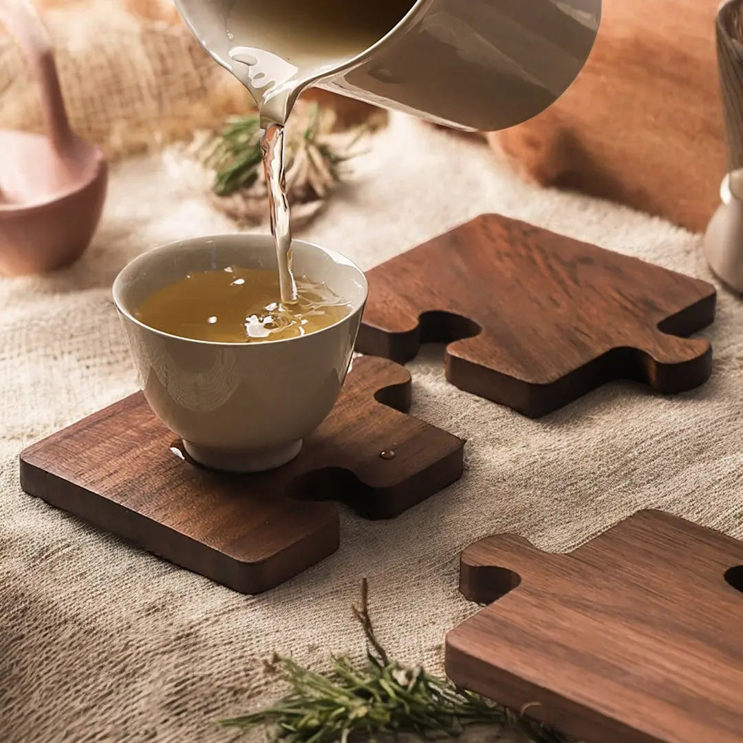 Set of four dark walnut jigsaw coasters protecting table during tea pouring