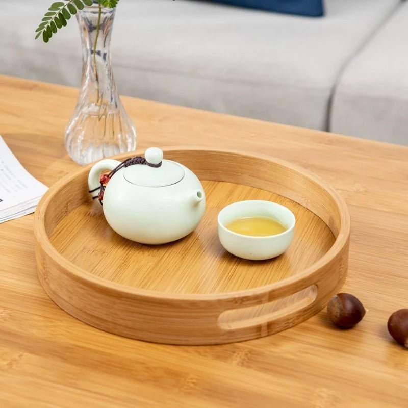 Natural bamboo serving tray styled with white teapot and cups for tea service on wooden table