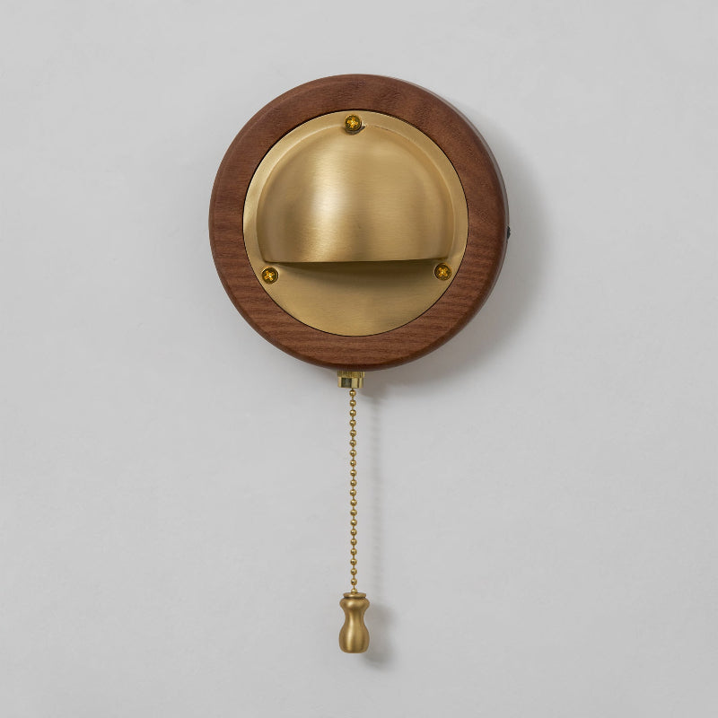 Round dark wood and brass pull chain wall sconce with visible grain detail