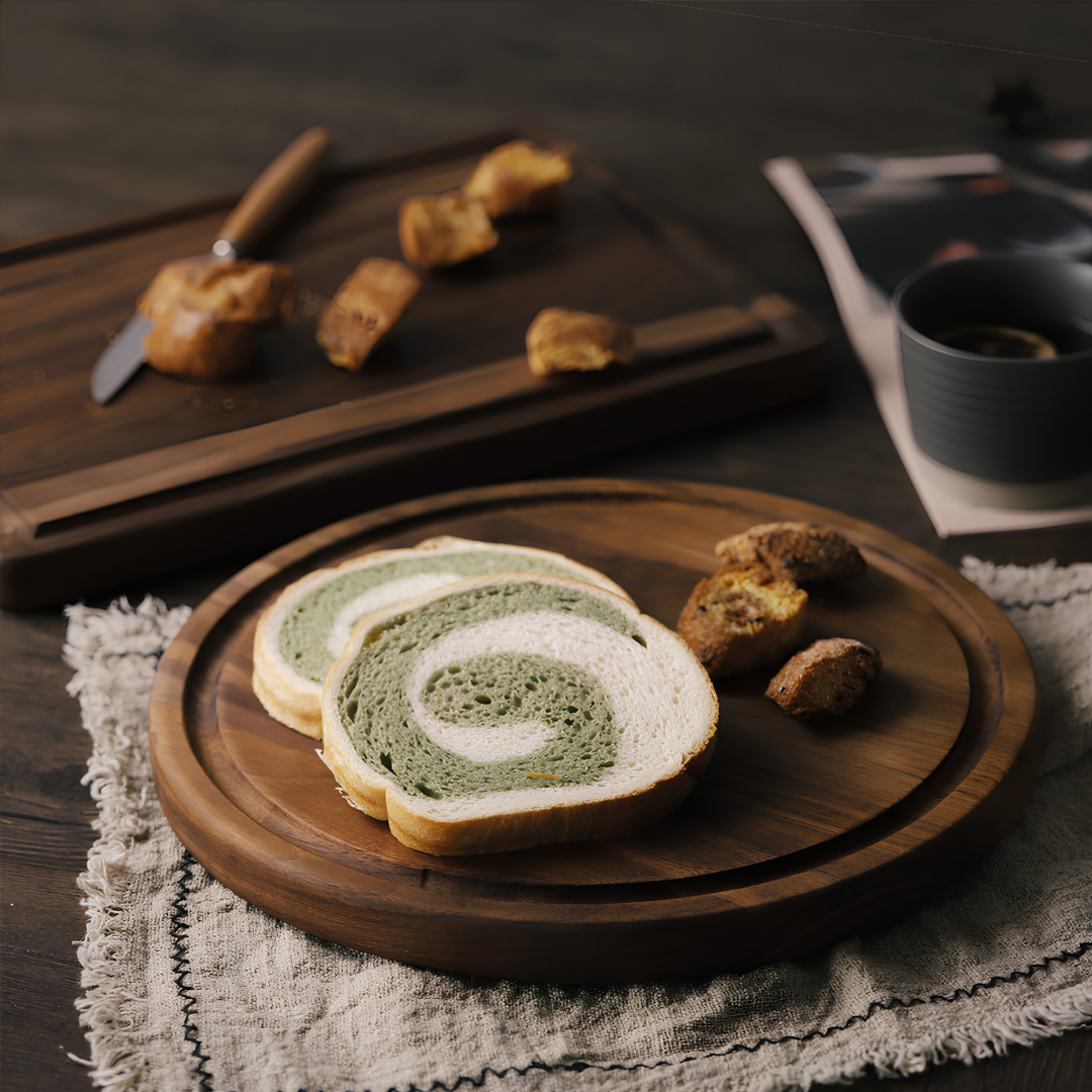 Round wooden serving platter with juice groove holding bread and pastries