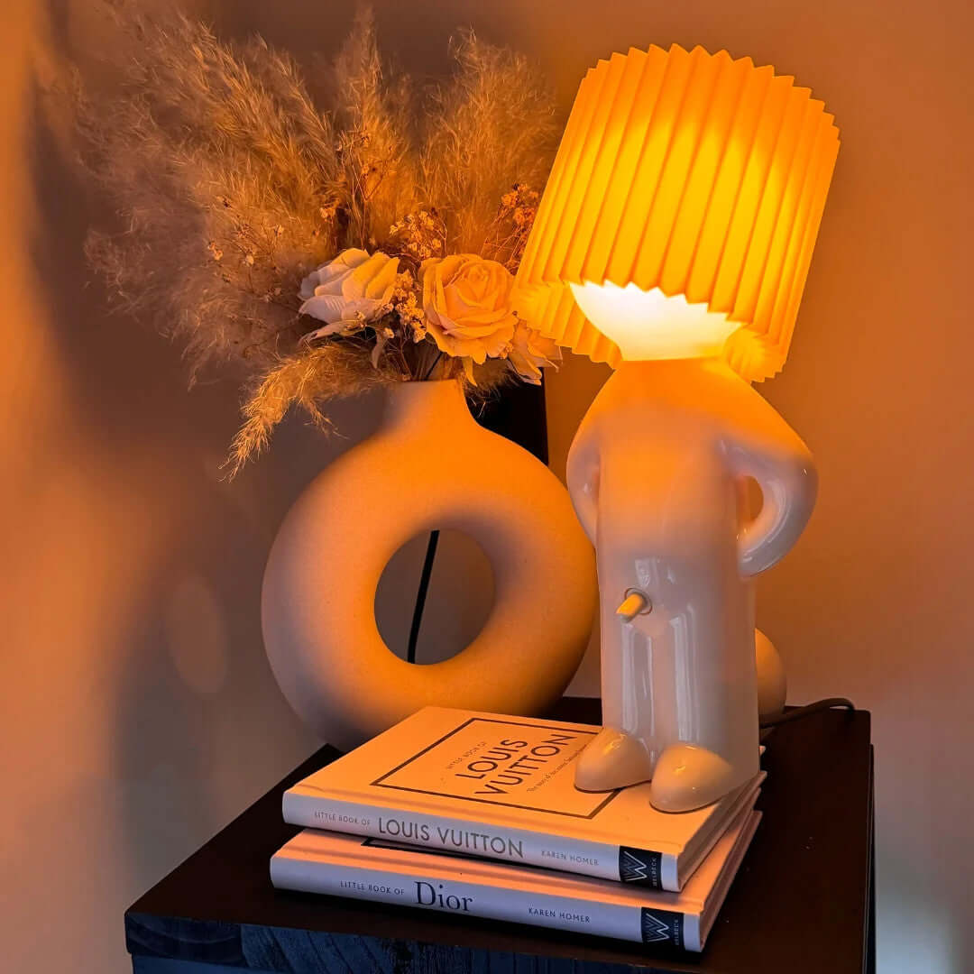 Yellow pleated lampshade on glossy white ceramic figurine desk lamp