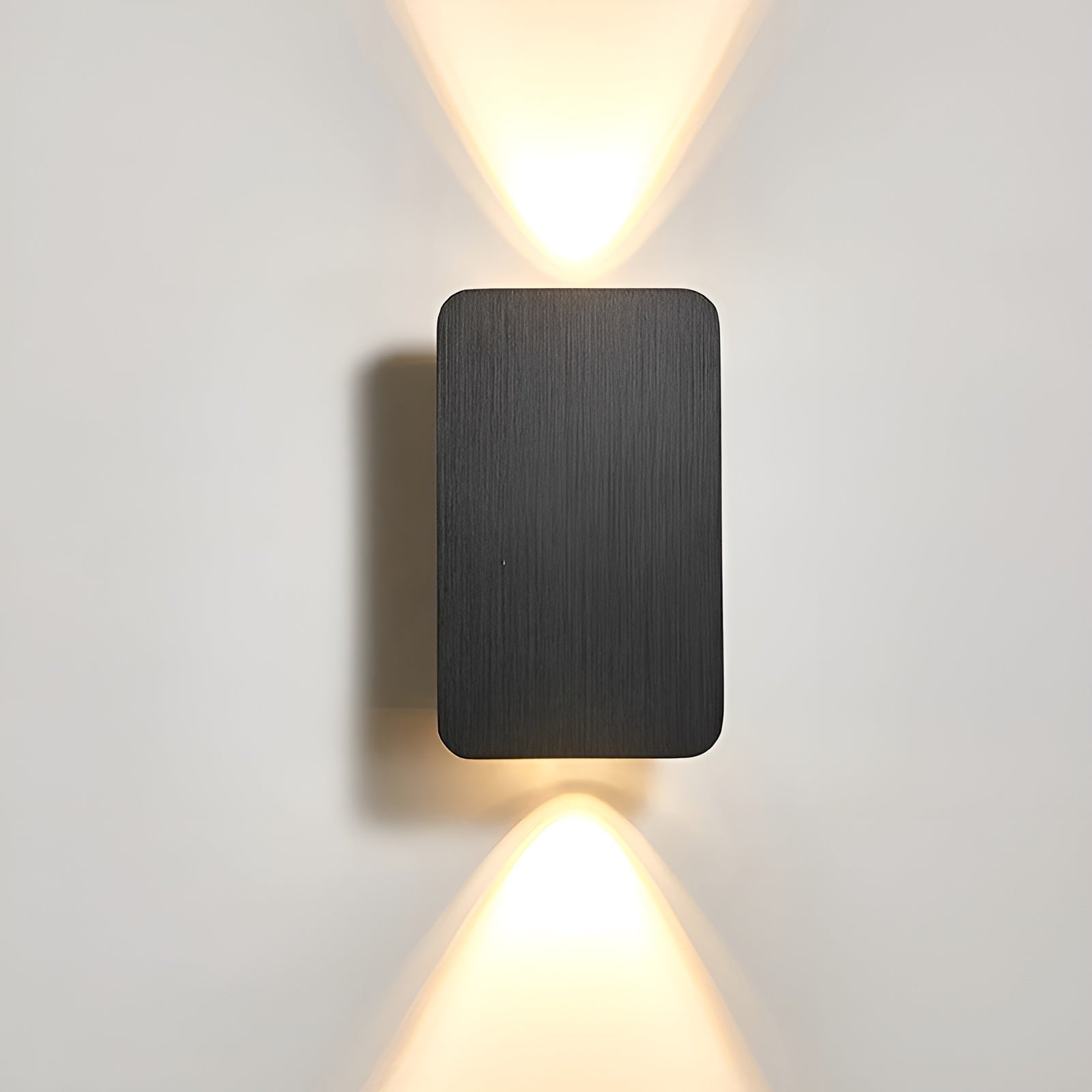 Matte black rectangular wall sconce with vertical brushed texture and dual beam lighting