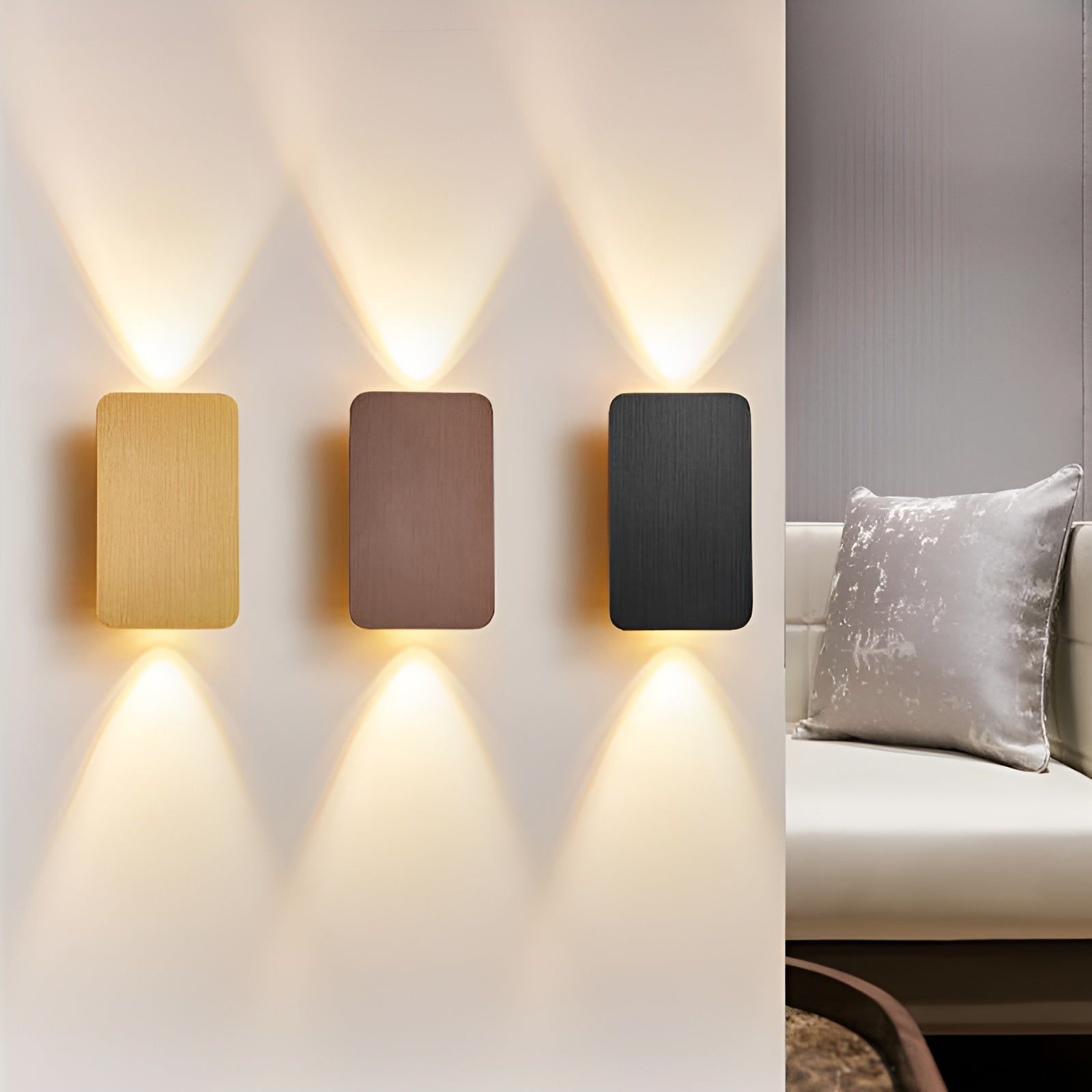 Gold, bronze, and black rectangular wall lamps flanking modern sofa with velvet pillow