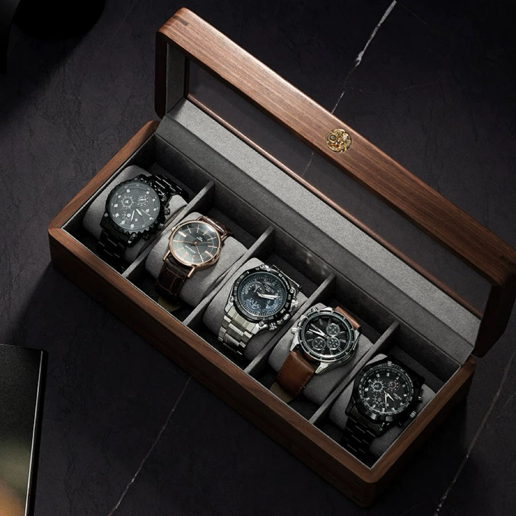 Rectangular wooden watch organizer with glass lid displaying four luxury timepieces