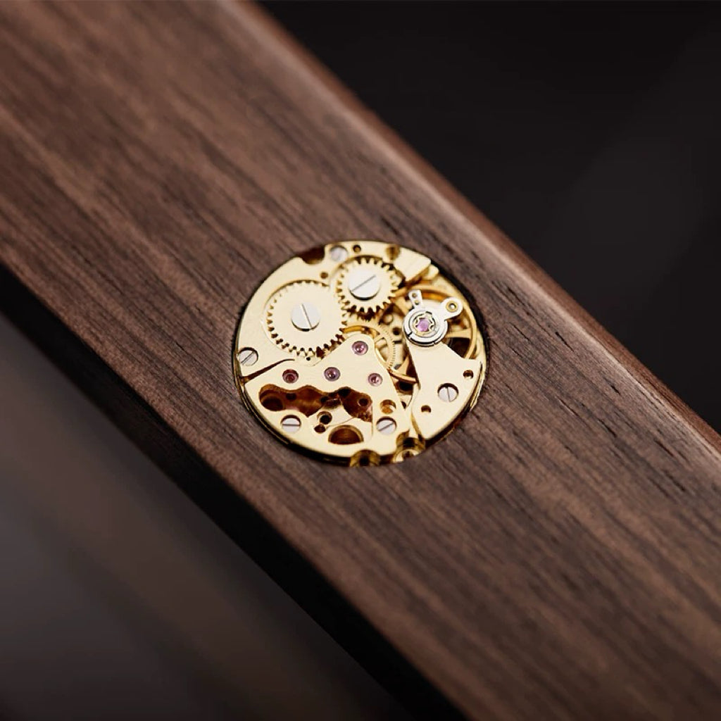 Close-up of gold mechanical watch movement on walnut wood grain surface